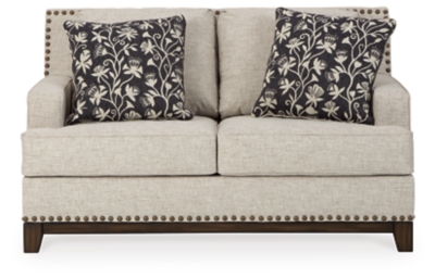 With its uniquely chic blend of elements, the Ballina loveseat breaks the rules in a beautiful way. Crisp and clean—with just a hint of classic flair—this designer loveseat stands out with its sleek track arms and prominent nailhead trim punctuating the linear profile. Truly setting this contemporary loveseat apart—an exposed walnut-tone rail for a high-end, furniture gallery aesthetic. Reversible cushions and decorative pillows in relaxed, muted hues make this loveseat befitting everything from modern farmhouse to urban chic spaces.Corner-blocked frame | Reversible cushions | High-resiliency foam cushions wrapped in thick poly fiber | Polyester upholstery | Throw pillows included | Pillows with soft polyfill | Exposed rail and feet with faux wood finish | Platform foundation system resists sagging 3x better than spring system after 20,000 testing cycles by providing more even support | Smooth platform foundation maintains tight, wrinkle-free look without dips or sags that can occur over time with sinuous spring foundations