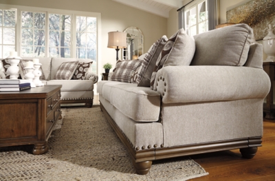 True classic character comes to life in the Harleson sofa. Set back pleated rolled arms and warm brown exposed frame with bun feet are beautifully traditional. Lovely detailing carries itself through the herringbone weave in the soft upholstery. Seat cushions reverse to maintain durable comfort. Vintage-inspired jumbo nailhead trim graces the design. Plaid and botanical pillows in dark brown are a timeless touch.Corner-blocked frame | Attached back and reversible seat cushions | High-resiliency foam cushions wrapped in thick poly fiber | 5 decorative pillows included | Pillows with soft polyfill | Polyester upholstery; Polyester/acrylic/linen and polyester pillows | Bronze-tone nailhead trim | Exposed feet with faux wood finish | Platform foundation system resists sagging 3x better than spring system after 20,000 testing cycles by providing more even support | Smooth platform foundation maintains tight, wrinkle-free look without dips or sags that can occur over time with sinuous spring foundations