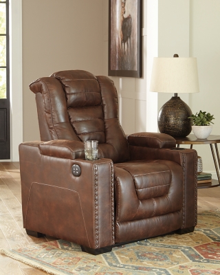 When it comes to style, you’ve got game. Rest assured, the Owner’s Box power recliner is sure to win you over with its ultra-cool looks and major league features. Showcasing all the bells and whistles, this designer recliner is inspired by sports car interiors—with a fabulous faux leather accentuated with horizontal channel tufting. An advanced one-touch power control with an Easy View™ power headrest puts you in the driver’s seat. Dual cup holders and armrests with hidden storage take the form and function to another level.One-touch power control with adjustable positions | Easy View™ adjustable headrest | Corner-blocked frame with metal reinforced seat | Attached cushions | High-resiliency foam cushions wrapped in thick poly fiber | Faux leather upholstery | Each armrest includes storage compartment and cup holder | Extended ottoman for enhanced comfort | Power cord included; UL Listed | Exposed feet with faux wood finish | Estimated Assembly Time: 15 Minutes