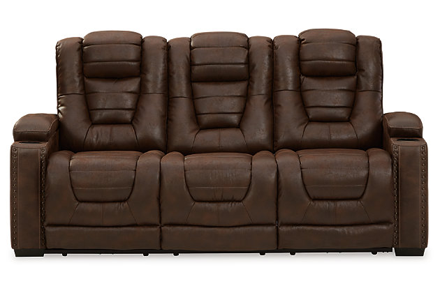 When it comes to style, you’ve got game. Rest assured, the Owner’s Box power reclining sofa is sure to win you over with its ultra-cool looks and major league features. Showcasing all the bells and whistles, this designer reclining sofa is inspired by sports car interiors—with a fabulous faux leather accentuated with horizonal channel tufting. An advanced one-touch power control with an Easy View™ power headrest puts you in the driver’s seat. Dual cup holders and armrests with hidden storage take the form and function to another level, while a middle seat with drop-down table, cup holders and docking station cater to your every want and need.Dual-sided recliner | One-touch power control with adjustable positions | Easy View™ adjustable headrest | Corner-blocked frame with metal reinforced seat | Attached cushions | High-resiliency foam cushions wrapped in thick poly fiber | Faux leather upholstery | Each armrest includes storage compartment and cup holder | Extended ottoman for enhanced comfort | Drop down table with 2 cup holders plus A/C power and USB ports for charging electronics | Power cord included; UL Listed | Exposed feet with faux wood finish | Estimated Assembly Time: 15 Minutes