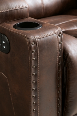 When it comes to style, you’ve got game. Rest assured, the Owner’s Box power recliner is sure to win you over with its ultra-cool looks and major league features. Showcasing all the bells and whistles, this designer recliner is inspired by sports car interiors—with a fabulous faux leather accentuated with horizontal channel tufting. An advanced one-touch power control with an Easy View™ power headrest puts you in the driver’s seat. Dual cup holders and armrests with hidden storage take the form and function to another level.One-touch power control with adjustable positions | Easy View™ adjustable headrest | Corner-blocked frame with metal reinforced seat | Attached cushions | High-resiliency foam cushions wrapped in thick poly fiber | Faux leather upholstery | Each armrest includes storage compartment and cup holder | Extended ottoman for enhanced comfort | Power cord included; UL Listed | Exposed feet with faux wood finish | Estimated Assembly Time: 15 Minutes