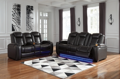 The Party Time power reclining sofa takes its cue from luxury automobiles with lattice- and cross-hatch stitching, for a richly tailored aesthetic that gives you plenty of reasons to celebrate. Sumptuously padded cushions and dramatic midnight black faux leather upholstery add to the indulgence. When it’s time to rev up the action, the sofa’s dual reclining bucket seats (middle seat is stationary), Easy View™ power adjustable headrests and center seat that folds down into a table keep you in the driver’s seat. Dual-sided recliner | One-touch power controls with adjustable positions | Easy View™ power adjustable headrests | Corner-blocked frame with metal reinforced seats | Attached backs and seat cushions | High-resiliency foam cushions wrapped in thick poly fiber | Polyester/polyurethane upholstery | Flip up padded armrests with hidden storage underneath | Drop down table with 2 cup holders and a handy docking station for charging electronics | Includes USB charging port in each power control | Flip up LED light (under center seat headrest) | Ambient blue LED lighting on cup holders and base for a theater-style experience | Power cord included; UL Listed | Estimated Assembly Time: 15 Minutes