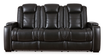The Party Time power reclining sofa takes its cue from luxury automobiles with lattice- and cross-hatch stitching, for a richly tailored aesthetic that gives you plenty of reasons to celebrate. Sumptuously padded cushions and dramatic midnight black faux leather upholstery add to the indulgence. When it’s time to rev up the action, the sofa’s dual reclining bucket seats (middle seat is stationary), Easy View™ power adjustable headrests and center seat that folds down into a table keep you in the driver’s seat. Ambient blue LED lighting on the base and cup holders completes the theater-style experience.Dual-sided recliner | Polyester/polyurethane upholstery | Corner-blocked frame with metal reinforced seats | Attached backs and seat cushions | High-resiliency foam cushions wrapped in thick poly fiber | One-touch power controls with adjustable positions | Easy View™ power adjustable headrests | Flip up padded armrests with hidden storage underneath | Drop down table with 2 cup holders and a handy docking station for charging electronics | Includes USB charging port in each power control | Flip up LED light (under center seat headrest) | LED lighting on the base and cup holders for theater-style experience | Power cord included; UL Listed | Estimated Assembly Time: 15 Minutes