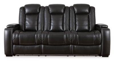 The Party Time power reclining sofa takes its cue from luxury automobiles with lattice- and cross-hatch stitching, for a richly tailored aesthetic that gives you plenty of reasons to celebrate. Sumptuously padded cushions and dramatic midnight black faux leather upholstery add to the indulgence. When it’s time to rev up the action, the sofa’s dual reclining bucket seats (middle seat is stationary), Easy View™ power adjustable headrests and center seat that folds down into a table keep you in the driver’s seat. Dual-sided recliner | One-touch power controls with adjustable positions | Easy View™ power adjustable headrests | Corner-blocked frame with metal reinforced seats | Attached backs and seat cushions | High-resiliency foam cushions wrapped in thick poly fiber | Polyester/polyurethane upholstery | Flip up padded armrests with hidden storage underneath | Drop down table with 2 cup holders and a handy docking station for charging electronics | Includes USB charging port in each power control | Flip up LED light (under center seat headrest) | Ambient blue LED lighting on cup holders and base for a theater-style experience | Power cord included; UL Listed | Estimated Assembly Time: 15 Minutes