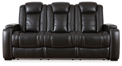 The Party Time power reclining sofa takes its cue from luxury automobiles with lattice- and cross-hatch stitching, for a richly tailored aesthetic that gives you plenty of reasons to celebrate. Sumptuously padded cushions and dramatic midnight black faux leather upholstery add to the indulgence. When it’s time to rev up the action, the sofa’s dual reclining bucket seats (middle seat is stationary), Easy View™ power adjustable headrests and center seat that folds down into a table keep you in the driver’s seat. Ambient blue LED lighting on the base and cup holders completes the theater-style experience.Dual-sided recliner | Polyester/polyurethane upholstery | Corner-blocked frame with metal reinforced seats | Attached backs and seat cushions | High-resiliency foam cushions wrapped in thick poly fiber | One-touch power controls with adjustable positions | Easy View™ power adjustable headrests | Flip up padded armrests with hidden storage underneath | Drop down table with 2 cup holders and a handy docking station for charging electronics | Includes USB charging port in each power control | Flip up LED light (under center seat headrest) | LED lighting on the base and cup holders for theater-style experience | Power cord included; UL Listed | Estimated Assembly Time: 15 Minutes