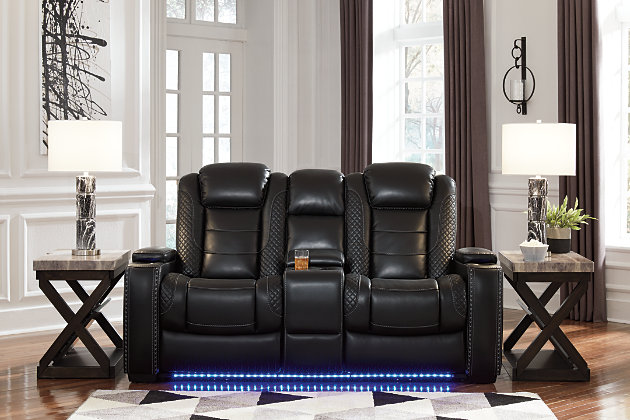 The Party Time power reclining loveseat takes its cue from luxury automobiles with lattice- and cross-hatch stitching, for a richly tailored aesthetic that gives you plenty of reasons to celebrate. Sumptuously padded cushions and dramatic midnight black faux leather upholstery add to the indulgence. When it’s time to rev up the action, the loveseat’s dual reclining bucket seats, Easy View™ power adjustable headrests and center console keep you in the driver’s seat. Dual-sided recliner | One-touch power controls with adjustable positions | Easy View™ power adjustable headrests | Corner-blocked frame with metal reinforced seats | Attached backs and seat cushions | High-resiliency foam cushions wrapped in thick poly fiber | Polyester/polyurethane upholstery | Includes USB charging port in each power control | Flip up padded armrests with hidden storage | Center console with cup holders and underneath storage | Ambient blue LED lighting on cup holders and base for a theater-style experience | Power cord included; UL Listed | Estimated Assembly Time: 15 Minutes