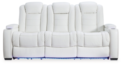 The Party Time power reclining sofa takes its cue from luxury automobiles with lattice and crosshatch stitching, for a richly tailored aesthetic that gives you plenty of reasons to celebrate. Sumptuously padded cushions and crisp white faux leather upholstery add to the indulgence. When it’s time to rev up the action, the dual reclining bucket seats (middle seat is stationary), Easy View™ power adjustable headrests and a center seat that folds down into a table keep you in the driver’s seat.Dual-sided recliner | Polyester/polyurethane upholstery | Corner-blocked frame with metal reinforced seat | Attached back and seat cushions | High-resiliency foam cushions wrapped in thick poly fiber | One-touch power control with adjustable positions, Easy View™ adjustable headrest and USB plug-in | Flip up padded armrests with hidden storage | Drop down table with 2 cup holders and a handy docking station for charging electronics | Flip up LED light (under center seat headrest) | Ambient blue LED lighting on cup holders and base for a theater-style experience | Power cord included; UL Listed | Estimated Assembly Time: 15 Minutes