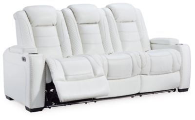 The Party Time power reclining sofa takes its cue from luxury automobiles with lattice and crosshatch stitching, for a richly tailored aesthetic that gives you plenty of reasons to celebrate. Sumptuously padded cushions and crisp white faux leather upholstery add to the indulgence. When it’s time to rev up the action, the dual reclining bucket seats (middle seat is stationary), Easy View™ power adjustable headrests and a center seat that folds down into a table keep you in the driver’s seat.Dual-sided recliner | Polyester/polyurethane upholstery | Corner-blocked frame with metal reinforced seat | Attached back and seat cushions | High-resiliency foam cushions wrapped in thick poly fiber | One-touch power control with adjustable positions, Easy View™ adjustable headrest and USB plug-in | Flip up padded armrests with hidden storage | Drop down table with 2 cup holders and a handy docking station for charging electronics | Flip up LED light (under center seat headrest) | Ambient blue LED lighting on cup holders and base for a theater-style experience | Power cord included; UL Listed | Estimated Assembly Time: 15 Minutes