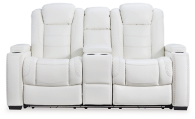 The Party Time power reclining loveseat takes its cue from luxury automobiles with lattice and crosshatch stitching, for a richly tailored aesthetic that gives you plenty of reasons to celebrate. Sumptuously padded cushions and crisp white faux leather upholstery add to the indulgence. When it’s time to rev up the action, the dual reclining bucket seats, Easy View™ power adjustable headrests and center console with docking station keep you in the driver’s seat. Dual-sided recliner | Polyester/polyurethane upholstery | Corner-blocked frame with metal reinforced seat | Attached back and seat cushions | High-resiliency foam cushions wrapped in thick poly fiber | One-touch power control with adjustable positions, Easy View™ adjustable headrest and USB plug-in | Flip up padded armrests with hidden storage | Center console with cup holders and underneath storage | Ambient blue LED lighting on cup holders and base for a theater-style experience | Power cord included; UL Listed | Estimated Assembly Time: 15 Minutes