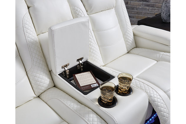 The Party Time power reclining loveseat takes its cue from luxury automobiles with lattice and crosshatch stitching, for a richly tailored aesthetic that gives you plenty of reasons to celebrate. Sumptuously padded cushions and crisp white faux leather upholstery add to the indulgence. When it’s time to rev up the action, the dual reclining bucket seats, Easy View™ power adjustable headrests and center console with docking station keep you in the driver’s seat. Dual-sided recliner | Polyester/polyurethane upholstery | Corner-blocked frame with metal reinforced seat | Attached back and seat cushions | High-resiliency foam cushions wrapped in thick poly fiber | One-touch power control with adjustable positions, Easy View™ adjustable headrest and USB plug-in | Flip up padded armrests with hidden storage | Center console with cup holders and underneath storage | Ambient blue LED lighting on cup holders and base for a theater-style experience | Power cord included; UL Listed | Estimated Assembly Time: 15 Minutes