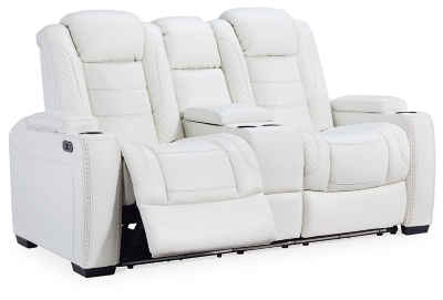 The Party Time power reclining loveseat takes its cue from luxury automobiles with lattice and crosshatch stitching, for a richly tailored aesthetic that gives you plenty of reasons to celebrate. Sumptuously padded cushions and crisp white faux leather upholstery add to the indulgence. When it’s time to rev up the action, the dual reclining bucket seats, Easy View™ power adjustable headrests and center console with docking station keep you in the driver’s seat. Dual-sided recliner | Polyester/polyurethane upholstery | Corner-blocked frame with metal reinforced seat | Attached back and seat cushions | High-resiliency foam cushions wrapped in thick poly fiber | One-touch power control with adjustable positions, Easy View™ adjustable headrest and USB plug-in | Flip up padded armrests with hidden storage | Center console with cup holders and underneath storage | Ambient blue LED lighting on cup holders and base for a theater-style experience | Power cord included; UL Listed | Estimated Assembly Time: 15 Minutes