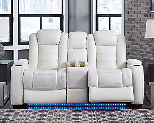 The Party Time power reclining loveseat takes its cue from luxury automobiles with lattice and crosshatch stitching, for a richly tailored aesthetic that gives you plenty of reasons to celebrate. Sumptuously padded cushions and crisp white faux leather upholstery add to the indulgence. When it’s time to rev up the action, the dual reclining bucket seats, Easy View™ power adjustable headrests and center console with docking station keep you in the driver’s seat. Dual-sided recliner | Polyester/polyurethane upholstery | Corner-blocked frame with metal reinforced seat | Attached back and seat cushions | High-resiliency foam cushions wrapped in thick poly fiber | One-touch power control with adjustable positions, Easy View™ adjustable headrest and USB plug-in | Flip up padded armrests with hidden storage | Center console with cup holders and underneath storage | Ambient blue LED lighting on cup holders and base for a theater-style experience | Power cord included; UL Listed | Estimated Assembly Time: 15 Minutes