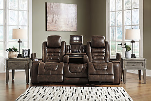If you’re looking for the perfect seat for gaming, lounging or just relaxing, look no further than the indulgent comfort of the Game Zone power reclining sofa. Sporting one-touch power controls, Easy View™ power adjustable headrests, cup holders, storage and chargers, this dual-sided reclining sofa has everything you need for binge-watching or power playing. Padded cushions with waterfall back design and pillow top arms offer plenty of support, while leather alternative upholstery is given tuck and roll styling for a well-edited aesthetic. The stationary middle seat has hidden depths, just fold it forward to reveal a table-top with cup holders, USB charging a storage pocket and overhead lights. How’s that for handy?Dual-sided recliner | Polyurethane/polyester tuck and roll upholstery | Corner-blocked frame with metal reinforced seat | Attached back and seat cushions | High-resiliency foam cushions wrapped in thick poly fiber | One-touch power controls with adjustable positions | Includes USB charging port in each power control | Easy View™ power adjustable headrests | Cup holders; flip up padded armrests with hidden storage underneath | Drop down table with 2 cup holders and a handy docking station for charging electronics | Flip up LED light (under center seat headrest) | Nailhead trim | Power cord included; UL Listed | Estimated Assembly Time: 15 Minutes