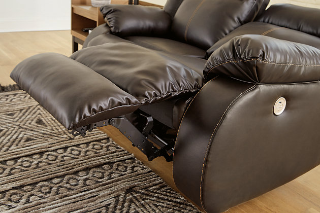 If highly contemporary looks and a heavenly feel sit well with you, rest your eyes on the Denoran reclining power sofa. Decadently soft, the easy-care faux leather upholstery is enriched with jumbo contrast stitching and dramatic cut-and-sew lines for fashion-forward flair. Radius cut arm frame adds cool, curvaceous interest. At your fingertips: one-touch power control with a zero-draw USB plug-in that’s not only convenient but also energy efficient. When it comes to high style at a down-to-earth price, this power reclining sofa really brings it home.Dual-sided recliner; middle seat remains stationary | One-touch power control with adjustable positions and zero-draw USB plug-in | Zero-draw technology only consumes power when the USB receptacle is in use | Vinyl/polyester/polyurethane upholstery | Corner-blocked frame with metal reinforced seat | Attached back and seat cushions | Exaggerated headrest | High-resiliency foam cushions wrapped in thick poly fiber | Power cord included; UL Listed