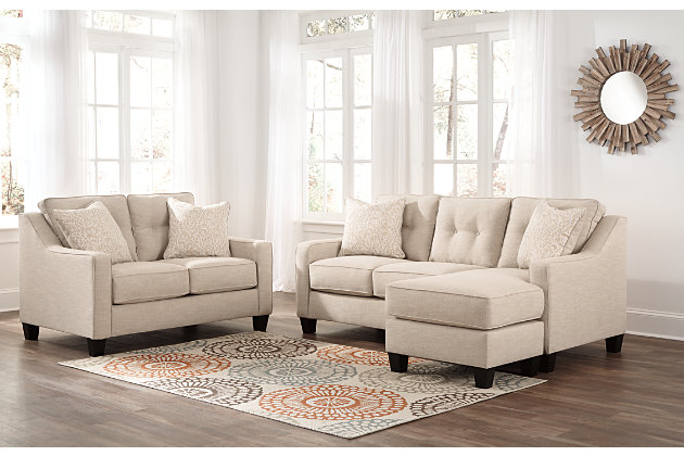 Whether you have kids or pets, or you simply love a low-maintenance way of life, the Aldie Nuvella® sofa chaise will surely have you sitting pretty. Plush to the touch yet incredibly durable, its stain- and abrasion-resistant Nuvella upholstery is a dream come true. And talk about no muss-no fuss design at its best. With its crisp, linear profile, sleek track arms and button-tufted back cushions, what a beautiful interpretation of mid-century modern style. Versatile chaise has a movable ottoman and reversible cushion and can be used on right or left side.Corner-blocked frame | Attached back and loose seat cushions | High-resiliency foam cushions wrapped in thick poly fiber | 2 accent pillows included | Polyester pillows with soft polyfill | Easy-clean polyester (Nuvella®) upholstery remains vibrant and resists stains | Clean fabric with mild soap and water, let air dry; for stubborn stains, use a solution of 1 cup bleach to 1 gallon water | Exposed feet with faux wood finish | Chaise can be positioned on either side (thanks to reversible seat cushion and movable ottoman)