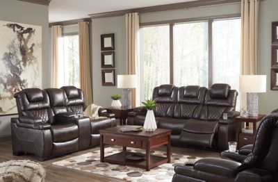 Your modern living room awaits with the Warnerton power reclining sofa. Complete with practical faux leather upholstery, one-touch power controls, adjustable headrests and USB ports, it makes finding the best seat in the house a breeze. What a perk that the center seat is crafted with a drop-down table with power/USB plug-ins and dual cup holders. Armrests with storage and cup holders keep drinks, snacks and remotes close by. Go ahead—treat yourself to a high-design home theater experience, priced to put you at ease.Dual-sided recliner; middle seat remains stationary | One-touch power controls with adjustable positions | Corner-blocked frame with metal reinforced seat | Attached cushions | High-resiliency foam cushions wrapped in thick poly fiber | Easy View™ power adjustable headrests | Each armrest with flip-top storage and cup holder | Drop-down table with AC power/USB plug-ins and 2 cup holders | USB charging port in power control | Polyester/polyurethane upholstery | Power cord included; UL Listed | Estimated Assembly Time: 30 Minutes