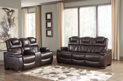 Your modern living room awaits with the Warnerton power reclining sofa. Complete with practical faux leather upholstery, one-touch power controls, adjustable headrests and USB ports, it makes finding the best seat in the house a breeze. What a perk that the center seat is crafted with a drop-down table with power/USB plug-ins and dual cup holders. Armrests with storage and cup holders keep drinks, snacks and remotes close by. Go ahead—treat yourself to a high-design home theater experience, priced to put you at ease.Dual-sided recliner; middle seat remains stationary | One-touch power controls with adjustable positions | Corner-blocked frame with metal reinforced seat | Attached cushions | High-resiliency foam cushions wrapped in thick poly fiber | Easy View™ power adjustable headrests | Each armrest with flip-top storage and cup holder | Drop-down table with AC power/USB plug-ins and 2 cup holders | USB charging port in power control | Polyester/polyurethane upholstery | Power cord included; UL Listed | Estimated Assembly Time: 30 Minutes