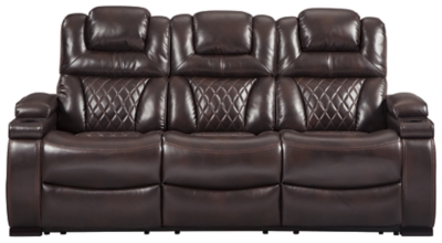 Your modern living room awaits with the Warnerton power reclining sofa. Complete with practical faux leather upholstery, one-touch power controls, adjustable headrests and USB ports, it makes finding the best seat in the house a breeze. What a perk that the center seat is crafted with a drop-down table with power/USB plug-ins and dual cup holders. Armrests with storage and cup holders keep drinks, snacks and remotes close by. Go ahead—treat yourself to a high-design home theater experience, priced to put you at ease.Dual-sided recliner; middle seat remains stationary | One-touch power controls with adjustable positions | Corner-blocked frame with metal reinforced seat | Attached cushions | High-resiliency foam cushions wrapped in thick poly fiber | Easy View™ power adjustable headrests | Each armrest with flip-top storage and cup holder | Drop-down table with AC power/USB plug-ins and 2 cup holders | USB charging port in power control | Polyester/polyurethane upholstery | Power cord included; UL Listed | Estimated Assembly Time: 30 Minutes