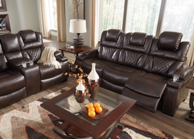 Your modern living room awaits with the Warnerton power reclining sofa. Complete with practical faux leather upholstery, one-touch power controls, adjustable headrests and USB ports, it makes finding the best seat in the house a breeze. What a perk that the center seat is crafted with a drop-down table with power/USB plug-ins and dual cup holders. Armrests with storage and cup holders keep drinks, snacks and remotes close by. Go ahead—treat yourself to a high-design home theater experience, priced to put you at ease.Dual-sided recliner; middle seat remains stationary | One-touch power controls with adjustable positions | Corner-blocked frame with metal reinforced seat | Attached cushions | High-resiliency foam cushions wrapped in thick poly fiber | Easy View™ power adjustable headrests | Each armrest with flip-top storage and cup holder | Drop-down table with AC power/USB plug-ins and 2 cup holders | USB charging port in power control | Polyester/polyurethane upholstery | Power cord included; UL Listed | Estimated Assembly Time: 30 Minutes