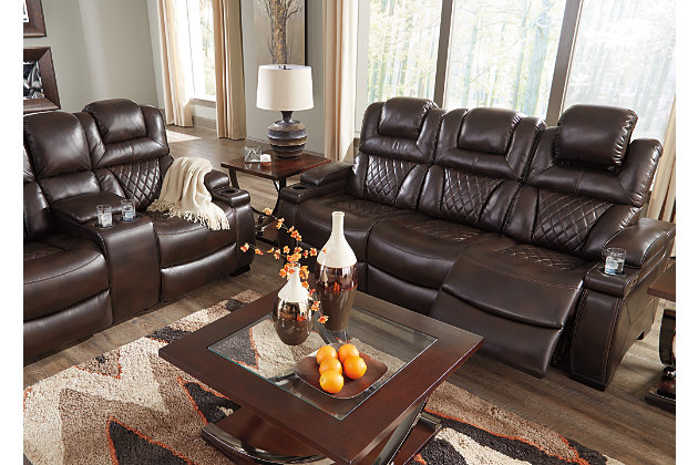 Your modern living room awaits with the Warnerton power reclining sofa. Complete with practical faux leather upholstery, one-touch power controls, adjustable headrests and USB ports, it makes finding the best seat in the house a breeze. What a perk that the center seat is crafted with a drop-down table with power/USB plug-ins and dual cup holders. Armrests with storage and cup holders keep drinks, snacks and remotes close by. Go ahead—treat yourself to a high-design home theater experience, priced to put you at ease.Dual-sided recliner; middle seat remains stationary | One-touch power controls with adjustable positions | Corner-blocked frame with metal reinforced seat | Attached cushions | High-resiliency foam cushions wrapped in thick poly fiber | Easy View™ power adjustable headrests | Each armrest with flip-top storage and cup holder | Drop-down table with AC power/USB plug-ins and 2 cup holders | USB charging port in power control | Polyester/polyurethane upholstery | Power cord included; UL Listed | Estimated Assembly Time: 30 Minutes