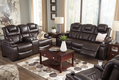 Your modern living room awaits with the Warnerton power reclining sofa. Complete with practical faux leather upholstery, one-touch power controls, adjustable headrests and USB ports, it makes finding the best seat in the house a breeze. What a perk that the center seat is crafted with a drop-down table with power/USB plug-ins and dual cup holders. Armrests with storage and cup holders keep drinks, snacks and remotes close by. Go ahead—treat yourself to a high-design home theater experience, priced to put you at ease.Dual-sided recliner; middle seat remains stationary | One-touch power controls with adjustable positions | Corner-blocked frame with metal reinforced seat | Attached cushions | High-resiliency foam cushions wrapped in thick poly fiber | Easy View™ power adjustable headrests | Each armrest with flip-top storage and cup holder | Drop-down table with AC power/USB plug-ins and 2 cup holders | USB charging port in power control | Polyester/polyurethane upholstery | Power cord included; UL Listed | Estimated Assembly Time: 30 Minutes