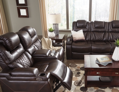 Your modern living room awaits with the Warnerton power reclining sofa. Complete with practical faux leather upholstery, one-touch power controls, adjustable headrests and USB ports, it makes finding the best seat in the house a breeze. What a perk that the center seat is crafted with a drop-down table with power/USB plug-ins and dual cup holders. Armrests with storage and cup holders keep drinks, snacks and remotes close by. Go ahead—treat yourself to a high-design home theater experience, priced to put you at ease.Dual-sided recliner; middle seat remains stationary | One-touch power controls with adjustable positions | Corner-blocked frame with metal reinforced seat | Attached cushions | High-resiliency foam cushions wrapped in thick poly fiber | Easy View™ power adjustable headrests | Each armrest with flip-top storage and cup holder | Drop-down table with AC power/USB plug-ins and 2 cup holders | USB charging port in power control | Polyester/polyurethane upholstery | Power cord included; UL Listed | Estimated Assembly Time: 30 Minutes