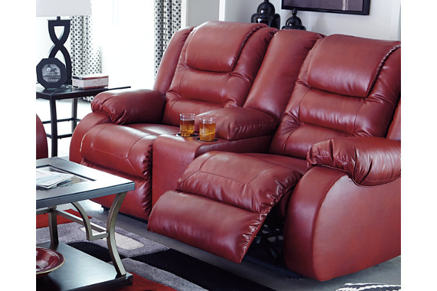 The Vacherie reclining loveseat puts comfort in style. Plush cushions are stitched to perfection. Ease back into the deep seating to rest your head on the supportive headrest. Supple fabric gives your room the high end look of leather with a spicy pop of color. You’ll love how easy it is to recline in infinite positions of relaxation. Drop a beverage in one of the cup holders, and enjoy sitting here for hours.Dual-sided recliner | Pull tab reclining motion | Lift-top storage console and 2 cup holders | Corner-blocked frame with metal reinforced seats | Attached back and seat cushions | High-resiliency foam cushions wrapped in thick poly fiber | Vinyl/polyester/polyurethane upholstery