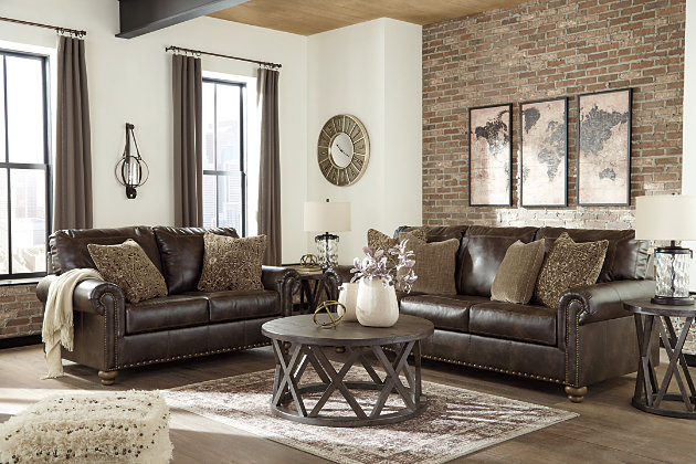 Enticing with a coffee brown faux leather, beautified with a gently weathered effect and designer stitching, the Nicorvo sofa merges a richly traditional sense of style with modern comfort. Roll arms, turned bun feet and prominent nailhead trim incorporate distinctive character. Four plush accent pillows are a sumptuous touch.Corner-blocked frame | Attached back and loose seat cushions | High-resiliency foam cushions wrapped in thick poly fiber | 4 throw pillows included | Pillows with soft polyfill | Polyester/polyurethane (faux leather) upholstery and polyester pillows | Nailhead trim | Exposed feet with faux wood finish | Platform foundation system resists sagging 3x better than spring system after 20,000 testing cycles by providing more even support | Smooth platform foundation maintains tight, wrinkle-free look without dips or sags that can occur over time with sinuous spring foundations
