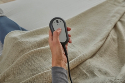Hand holding remote over fabric-covered surface with textured weave