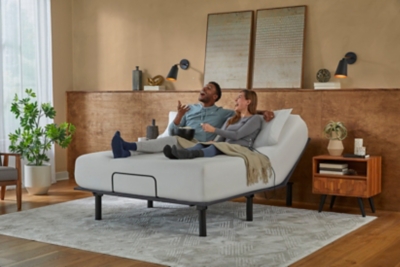 People sitting on a bed with someone relaxing under throws