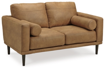 For a fresh spot in your space, turn to the Arroyo loveseat. This invigorating piece breathes warmth into your home with its striking caramel faux leather upholstery, modern bolster pillows and tapered legs. Wind down at the end of a long day when you sink into this canyon of comfort.Corner-blocked frame | High-resiliency foam cushions wrapped in thick poly fiber | Non-reversible loose seat and back cushions | Metal seat base | Polyester and polyurethane (faux leather) upholstery | 2 bolster pillows | Exposed legs with faux wood finish | Minor assembly (simply attach legs) | Estimated Assembly Time: 15 Minutes