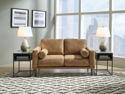 For a fresh spot in your space, turn to the Arroyo loveseat. This invigorating piece breathes warmth into your home with its striking caramel faux leather upholstery, modern bolster pillows and tapered legs. Wind down at the end of a long day when you sink into this canyon of comfort.Corner-blocked frame | High-resiliency foam cushions wrapped in thick poly fiber | Non-reversible loose seat and back cushions | Metal seat base | Polyester and polyurethane (faux leather) upholstery | 2 bolster pillows | Exposed legs with faux wood finish | Minor assembly (simply attach legs) | Estimated Assembly Time: 15 Minutes