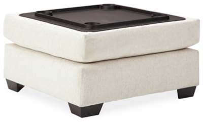 Let it snow. Doubling your pleasure with its combination of form and function, the Cambri storage ottoman in a snow-tone chenille fabric invites you to stretch your style in an easy-elegant way. Whether your aesthetic is urban hip or suburban chic, this posh ottoman with removable cushioned top and loads of handy storage is sure to look and feel right at home. And how’s this for a welcome surprise: a built-in tabletop with cup holders on the flip side!Corner-blocked frame | High-resiliency foam cushion wrapped in thick poly fiber | Polyester upholstery | Storage under cushioned removable top | Built-in tabletop/cup holders on reverse side of removable cushion | Exposed legs with faux wood finish