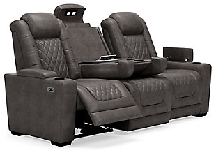 The Hyllmont power reclining sofa in trendy gray is proof of just how far recliners have come when it comes to form and function. Ultra cool and contemporary, this fully loaded power reclining sofa makes it so easy to social distance and make home your haven. Dressed to impress with diamond stitching inspired by sports car interiors, this reclining sofa is covered in a fabulous faux leather with pebbled effect for authenticity. High-tech advancements include a one-touch power control with Easy View™ adjustable headrest and USB plug-in and a drop-down table with cup holders, flip-up light and AC power/USB plug-ins. Dual-sided recliner | One-touch power control with adjustable positions, Easy View™ adjustable headrest and USB plug-in | Corner-blocked frame with metal reinforced seat | Attached cushions | High-resiliency foam cushions wrapped in thick poly fiber | Each armrest with hidden storage and cup holder | Drop-down center table with 2 cup holders, flip-up light and hidden AC power and USB ports | Faux leather polyester upholstery | Power cord included; UL Listed | Exposed tapered feet | Estimated Assembly Time: 15 Minutes