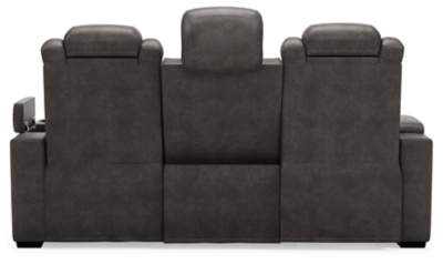 The Hyllmont power reclining sofa in trendy gray is proof of just how far recliners have come when it comes to form and function. Ultra cool and contemporary, this fully loaded power reclining sofa makes it so easy to social distance and make home your haven. Dressed to impress with diamond stitching inspired by sports car interiors, this reclining sofa is covered in a fabulous faux leather with pebbled effect for authenticity. High-tech advancements include a one-touch power control with Easy View™ adjustable headrest and USB plug-in and a drop-down table with cup holders, flip-up light and AC power/USB plug-ins. Dual-sided recliner | One-touch power control with adjustable positions, Easy View™ adjustable headrest and USB plug-in | Corner-blocked frame with metal reinforced seat | Attached cushions | High-resiliency foam cushions wrapped in thick poly fiber | Each armrest with hidden storage and cup holder | Drop-down center table with 2 cup holders, flip-up light and hidden AC power and USB ports | Faux leather polyester upholstery | Power cord included; UL Listed | Exposed tapered feet | Estimated Assembly Time: 15 Minutes