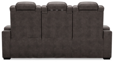 The Hyllmont power reclining sofa in trendy gray is proof of just how far recliners have come when it comes to form and function. Ultra cool and contemporary, this fully loaded power reclining sofa makes it so easy to social distance and make home your haven. Dressed to impress with diamond stitching inspired by sports car interiors, this reclining sofa is covered in a fabulous faux leather with pebbled effect for authenticity. High-tech advancements include a one-touch power control with Easy View™ adjustable headrest and USB plug-in and a drop-down table with cup holders, flip-up light and AC power/USB plug-ins. Dual-sided recliner | One-touch power control with adjustable positions, Easy View™ adjustable headrest and USB plug-in | Corner-blocked frame with metal reinforced seat | Attached cushions | High-resiliency foam cushions wrapped in thick poly fiber | Each armrest with hidden storage and cup holder | Drop-down center table with 2 cup holders, flip-up light and hidden AC power and USB ports | Faux leather polyester upholstery | Power cord included; UL Listed | Exposed tapered feet | Estimated Assembly Time: 15 Minutes