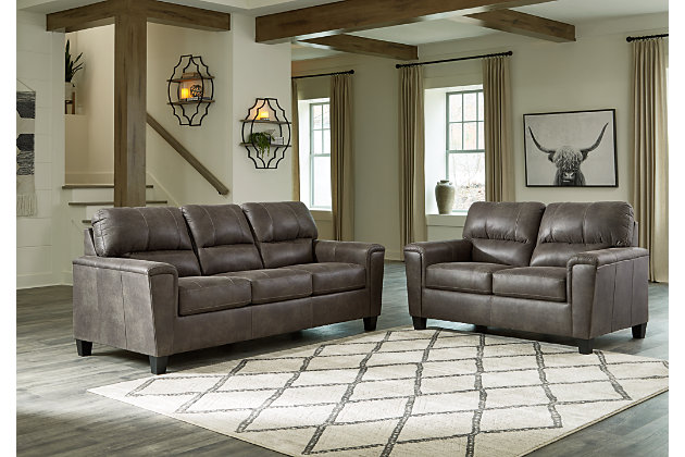 If you love the cool look of leather but long for the warm feel of fabric, you can take comfort in the Navi 2-piece set with sofa and loveseat. Wrapped in a fabulous faux leather with a weathered hue and hint of pebbly texture to resemble the real deal, this decidedly modern ensemble proves less is more. Elements include angled side profiling and track armrests wrapped with a layer of pillowy softness for that little something extra. Prominent jumbo stitching and clean-lined divided back styling lend fashion-forward flair.Includes 2 pieces: sofa and loveseat | Corner-blocked frame | Attached back and loose seat cushions | High-resiliency foam cushions wrapped in thick poly fiber | Faux leather upholstery  | Exposed feet with faux wood finish | Platform foundation system resists sagging 3x better than spring system after 20,000 testing cycles by providing more even support | Smooth platform foundation maintains tight, wrinkle-free look without dips or sags that can occur over time with sinuous spring foundations