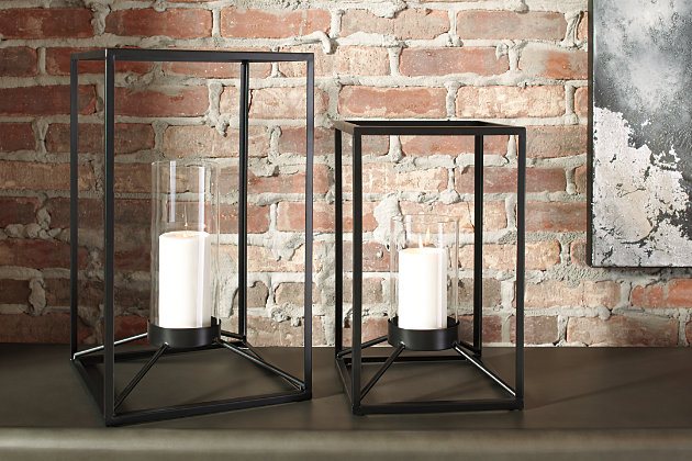 The minimalistic Demtrois 2-piece lantern set lights up your home in a sleek way. Black finished metal is beautifully crafted in a linear manner. Perfect for indoor or outdoor use. Place the candle of your choosing in the clear glass to make these lanterns your own.Includes 2 lanterns (large and small) | Made of metal and glass | Each lantern holds a 3” pillar candle (not included) | Suitable for indoor/outdoor use | Clean with a soft, dry cloth