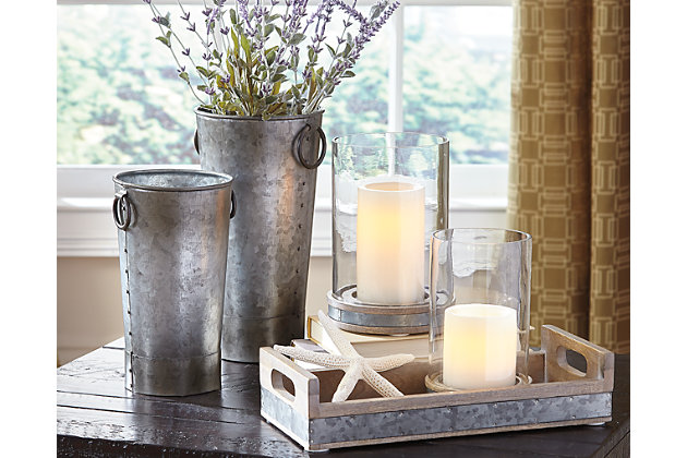 Industrial farmhouse design proliferates in the Donae 5-piece accessory set. Galvanized metal flows from the antiqued vases to the banding around the natural wood of the tray and candle holders. Soften the vibe by adding fresh greenery and pleasantly scented candles.Includes 2 candle holders, tray and 2 vases | Made of galvanized finished metal and natural wood | Candle holder holds 3" pillar candles (candles not included) | Clean with a soft, dry cloth