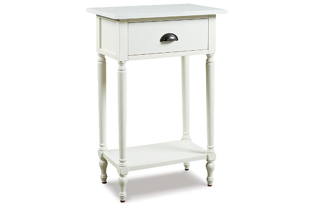 The perfect complement to any sofa, the Juinville accent table embodies quintessential vintage charm. It’s casually cool with a bronze-tone cupped drawer pull, turned legs, a framed drawer front and a classic white finish. You’ll love how the convenient drawer stores remotes and catchalls with ease. Last, but certainly not least, the bottom shelf is a hot spot for decor accents or an extra bin for tip-top organization in spaces.Made of veneers, wood and engineered wood | White finish | 1 smooth-gliding drawer, 1 lower shelf | Antique bronze-tone finished metal drawer pull | Assembly required | Estimated Assembly Time: 15 Minutes