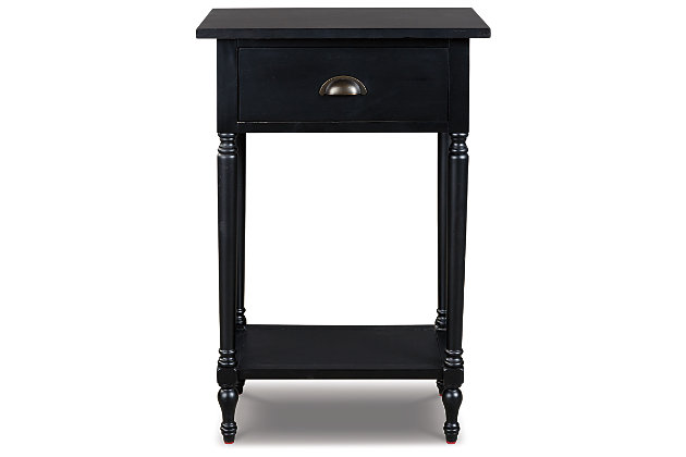 The perfect complement to any sofa, the Juinville accent table embodies quintessential vintage charm. It’s casually cool with a bronze-tone cupped drawer pull, turned legs, a framed drawer front and a classic black finish. You’ll love how the convenient drawer stores remotes and catchalls with ease. Last, but certainly not least, the bottom shelf is a hot spot for decor accents or an extra bin for tip-top organization in small spaces.Made of veneers, wood and engineered wood | Black finish | 1 smooth-gliding drawer, 1 lower shelf | Antique bronze-tone finished metal drawer pull | Assembly required | Estimated Assembly Time: 15 Minutes
