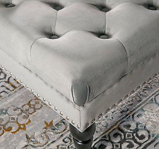 Square tufted ottoman on metal casters brings high style and versatility to your living space. Perfect as a footrest or coffee table, it wows with a tufted top and velvety soft gray fabric. Brushed silvertone nailheads accent the side, while turned black legs complete the richly traditional look.Made of birch wood | Foam cushioned seat covered in velvet polyester upholstery | Tufted top | Brushed silvertone nailhead trim | Black finished legs | Metal casters | Assembly required