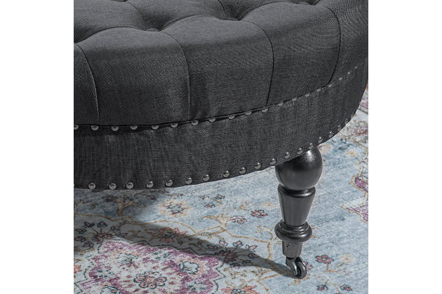 Round tufted ottoman on metal casters brings high style and versatility to your living space. Perfect as a footrest or coffee table, it wows with a tufted top and feel-good charcoal linen fabric. Silvertone nailheads accent the side, while turned black legs complete the richly traditional look.Made of birch wood | Foam cushioned seat covered in charcoal linen upholstery | Tufted top | Silvertone nailhead trim | Black finished legs | Metal casters | Assembly required