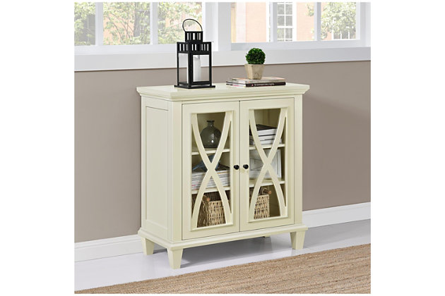 Say hello to style and goodbye to clutter with this simply elegant accent cabinet in ivory. Loaded with versatility, this 2-door storage cabinet with trio-level storage is dressed to impress with decorative mouldings and glass-front double doors with curved X overlays. What a striking way to master the art of organization.Made of engineered wood | 2 doors with glass panels | 2 shelves (3 levels) of storage | Black knobs | Assembly required