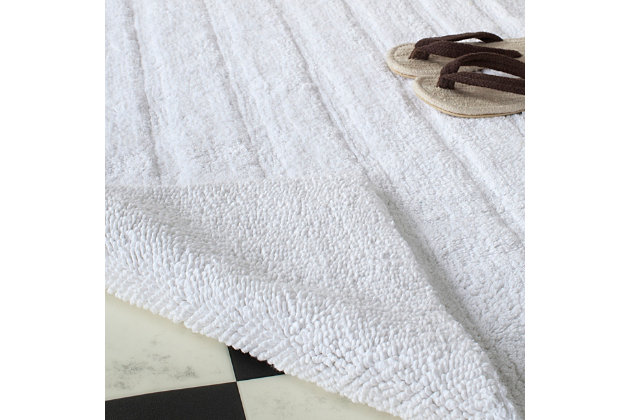 Add a lavish spa feel to the bath with this soft, fabulously functional, striped hand-tufted bath mat. Indulge in the luxury of plush and absorbent cotton every time you step on this reversible bath mat. One side is ribbed in elegantly simple vertical bands, while the other side is solid texture, all crafted from a deluxe 3000 grams of pure cotton.Set of 2 | 100% fine Indian cotton | Hand-tufted | White | Reversible (no backing) | Rug pad recommended to avoid shifting and sliding | Imported