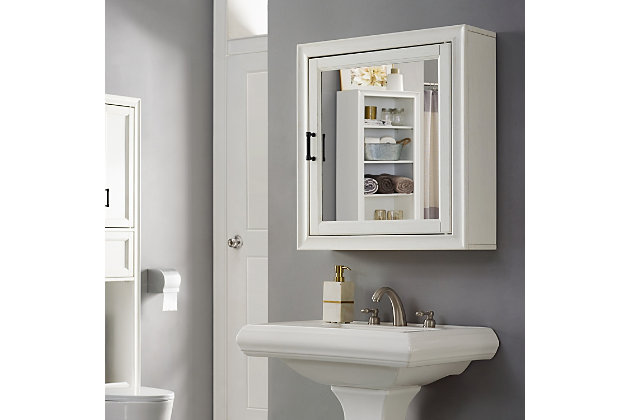 Bring a sense of order to your bathroom with this chic mirrored cabinet. Designed to add appeal while hiding its true function, its cottage styling and discreet cabinet storage provide an elegant use of space. At home in the tightest or most spacious bath, its compact size allows you to live large in small places.Pine frame with birch veneer | White finish | Metal hardware with distressed brass-tone finish | Mirrored door opens to reveal cabinet storage | Ready to hang | Assembly required