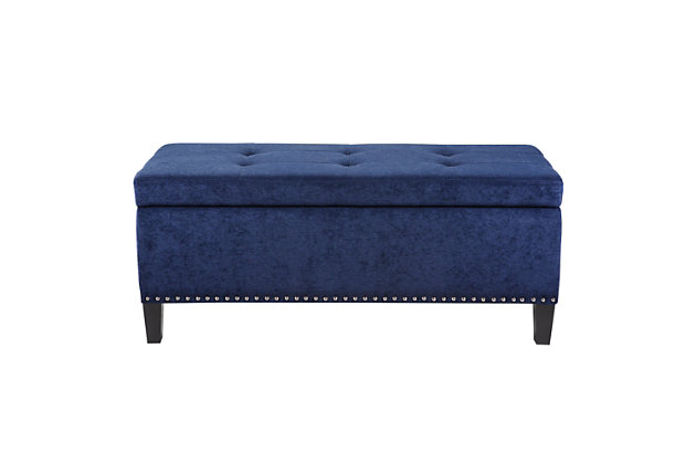 The modern Shandra II Storage Bench organizes linens and impresses with its stylish details. Featuring an elegant blue fabric with black noir legs, it provides the perfect functional finishing touch for your space. Made with wood | Legs with black finish | Polyester upholstery | High-density foam filling | Silvertone nailhead trim | Button-tufted detailing | Interior storage