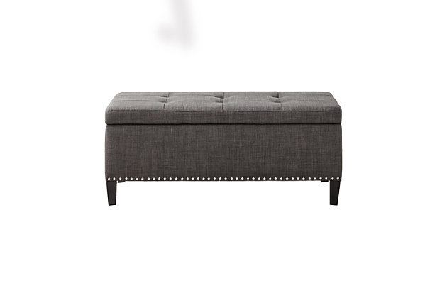 The modern Shandra II Storage Bench organizes linens and impresses with its stylish details. Featuring an elegant gray linen fabric with black noir legs, it provides the perfect functional finishing touch for your space. Made with wood | Legs with black finish | Polyester upholstery | High-density foam filling | Silvertone nailhead trim | Button-tufted detailing | Interior storage