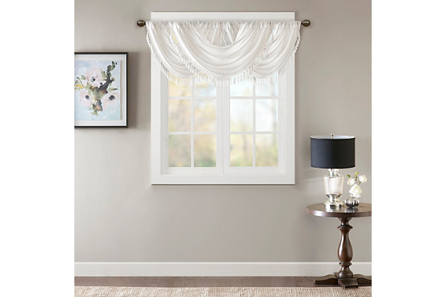Bring style and sophistication to your windows, with our Elena Waterfall window valance. This classy white valance showcases rich center draping details and a beautiful tassel trim, combined with the faux silk fabric for a rich sheen and stylish update. Features added lining and a rod pocket top finish; fits up to 1.25" diameter rod. Part of our decorative valance collection, this valance is perfect as a stylish addition to any small window or even better as a layering piece to dress up any window panel. This window valance is also OEKO-TEX certified, meaning it does not contain any harmful substances or chemicals, ensuring quality comfort and wellness. Multiple valances used to create this look.Imported | Faux silk luxe light sheen fabric window valance | Center waterfall drape design | Fits up 1.25" diameter rod | Tassel trim embellishment detailing | Oeko-tex certified, includes no harmful substances or chemicals (# bj025 173578) | Added lining for finish touch | Coordinating window panel available and sold separately | Machine washable for easy care
