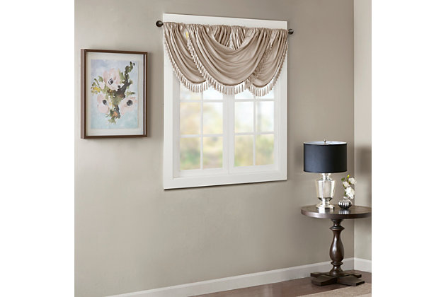 Bring style and sophistication to your windows, with our Elena Waterfall window valance. This classy champagne valance showcases rich center draping details and a beautiful tassel trim, combined with the faux silk fabric for a rich sheen and stylish update. Features added lining and a rod pocket top finish; fits up to 1.25" diameter rod. Part of our decorative valance collection, this valance is perfect as a stylish addition to any small window or even better as a layering piece to dress up any window panel. This window valance is also OEKO-TEX certified, meaning it does not contain any harmful substances or chemicals, ensuring quality comfort and wellness. Multiple valances used to create this look.Imported | Faux silk luxe light sheen fabric window valance | Center waterfall drape design | Fits up 1.25" diameter rod | Tassel trim embellishment detailing | Oeko-tex certified, includes no harmful substances or chemicals (# bj025 173578) | Added lining for finish touch | Coordinating window panel available and sold separately | Machine washable for easy care